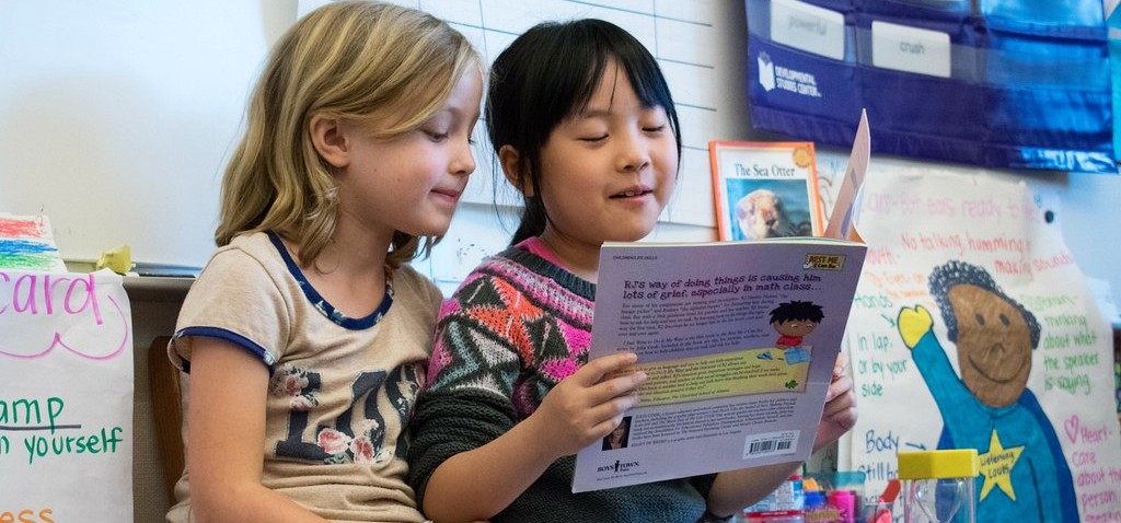 Two children sit together and read a book